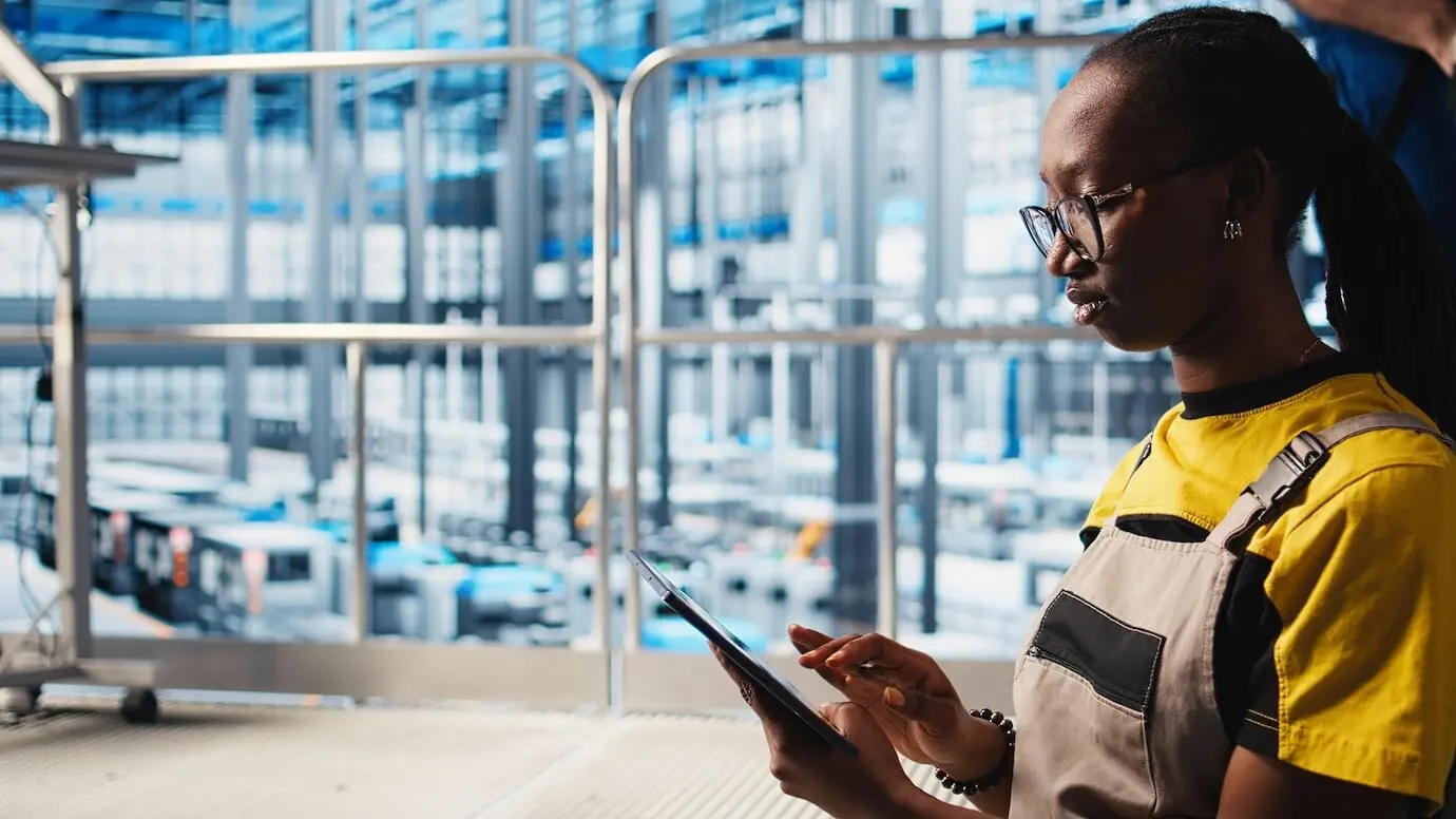 Работник умной фабрики использует планшет для сбора и анализа данных.